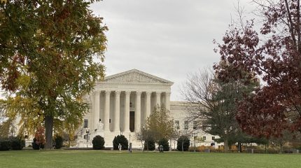 Supreme Court building seen from a distance surrounded by trees