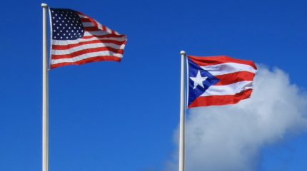 American flag and Puerto Rico flag against blue sky