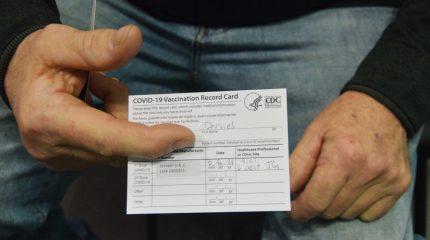 close up photo of man's hands holding vaccine card