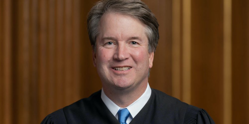 brett kavanaugh wearing judicial robe and sitting with hands crossed in lap