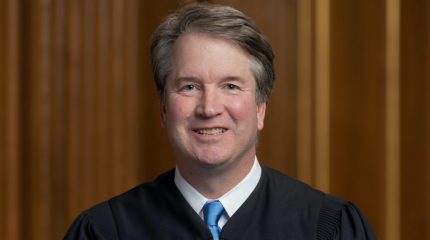 brett kavanaugh wearing judicial robe and sitting with hands crossed in lap