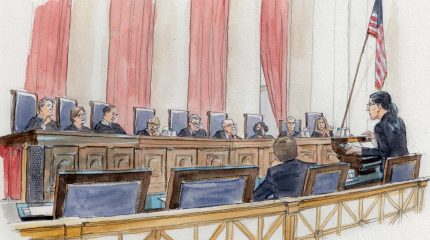 woman at lectern speaking to nine justices sitting on elevated bench