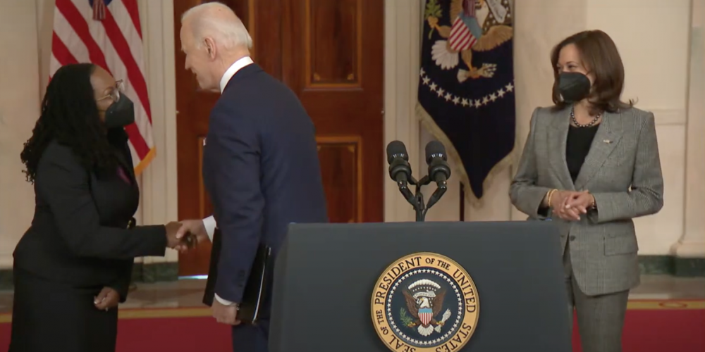 Judge Ketanji Brown Jackson shakes hands with the President, the Vice President watches them.