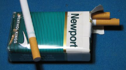 opened cigarette pack with Newport logo. one loose cigarette.