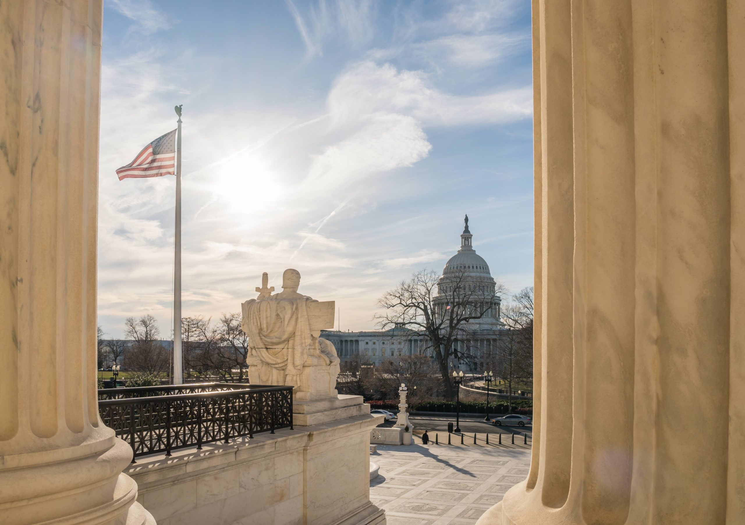 View of the US Capitol from the United States Supreme Court in Washington, DC with blue sky and US flag