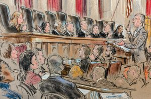 Man speaks to justices on bench while crowd looks on. 