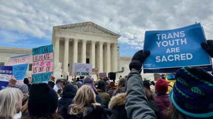 A crowd holding signs outside the Supreme Court