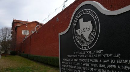 Texas state historic marker sign in front of prison wall